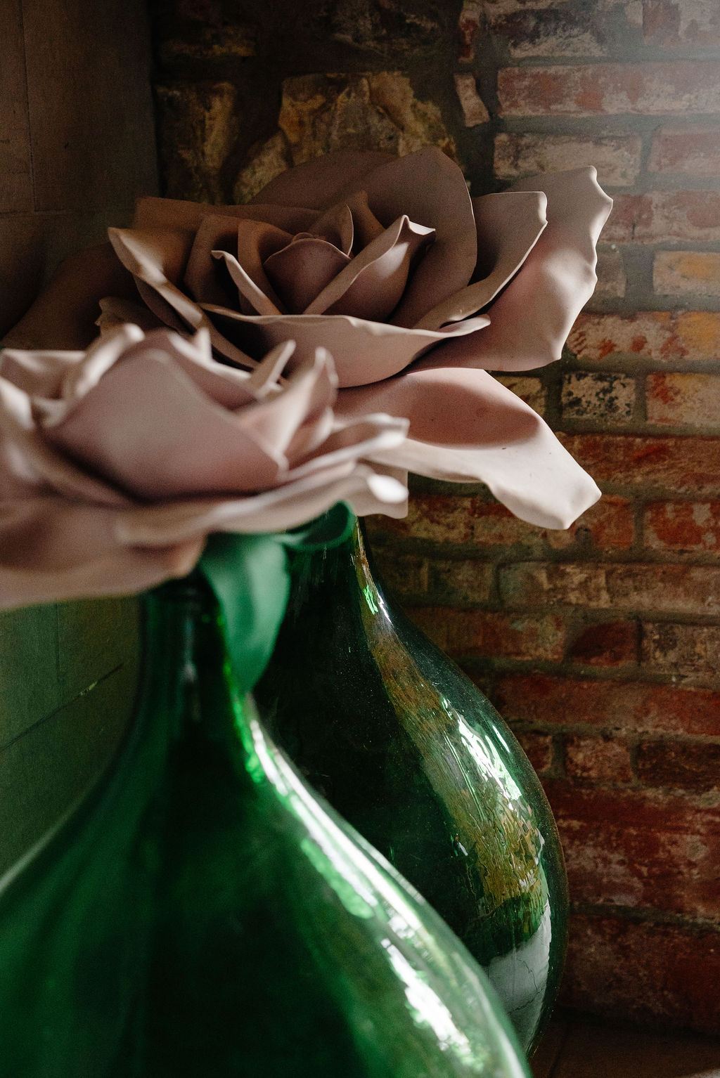Una rosa di carta fatta a mano, appoggiata a una damigiana verde